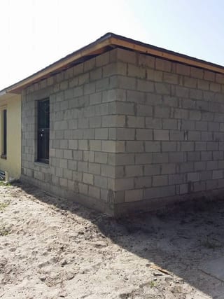 Bare concrete block addition with wood fascia and a framed doorway, ready for stucco