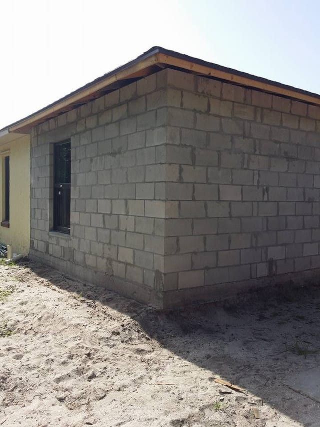Bare concrete block addition with wood fascia and a framed doorway, ready for stucco