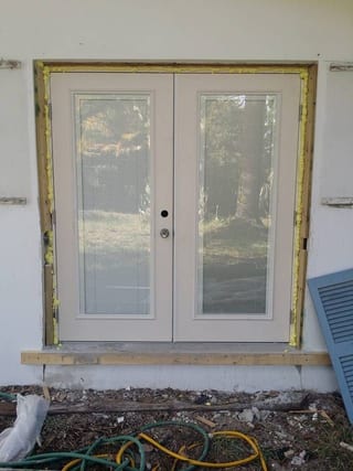 Newly installed french doors with raw framing and expanding foam before stucco