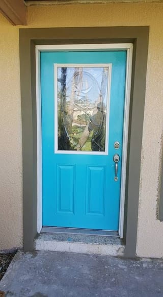 Finished wall around a bright turquoise front door, the repair blended into the existing texture
