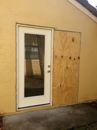 Yellow stucco wall with raw plywood patch before stucco infill
