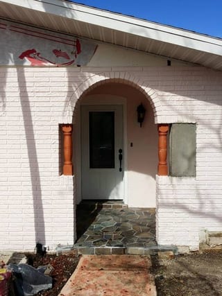 Painted-pink brick entry arch with raw brick and weathered front before refinish