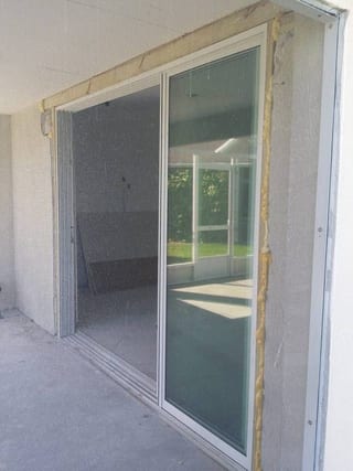 New sliding patio door with raw wood jamb framing and expanding foam before stucco