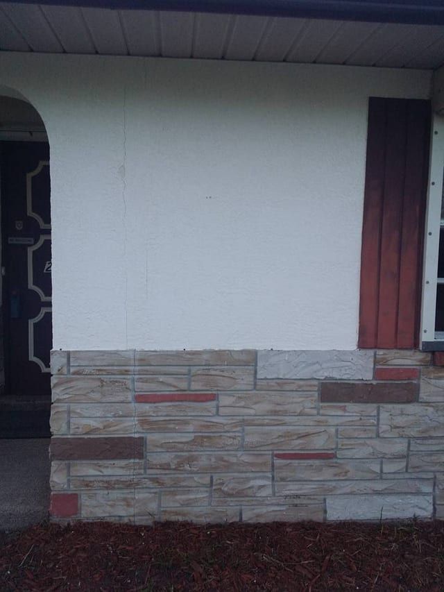 The same wall re-finished to an even white, cut in clean along the top of the stone